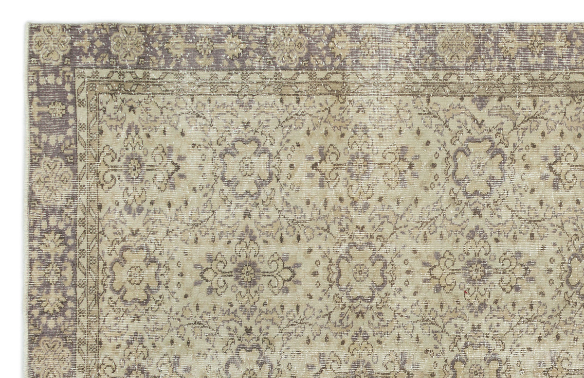Beige and muted purple vintage-style rug with a distressed floral medallion pattern and a decorative border.