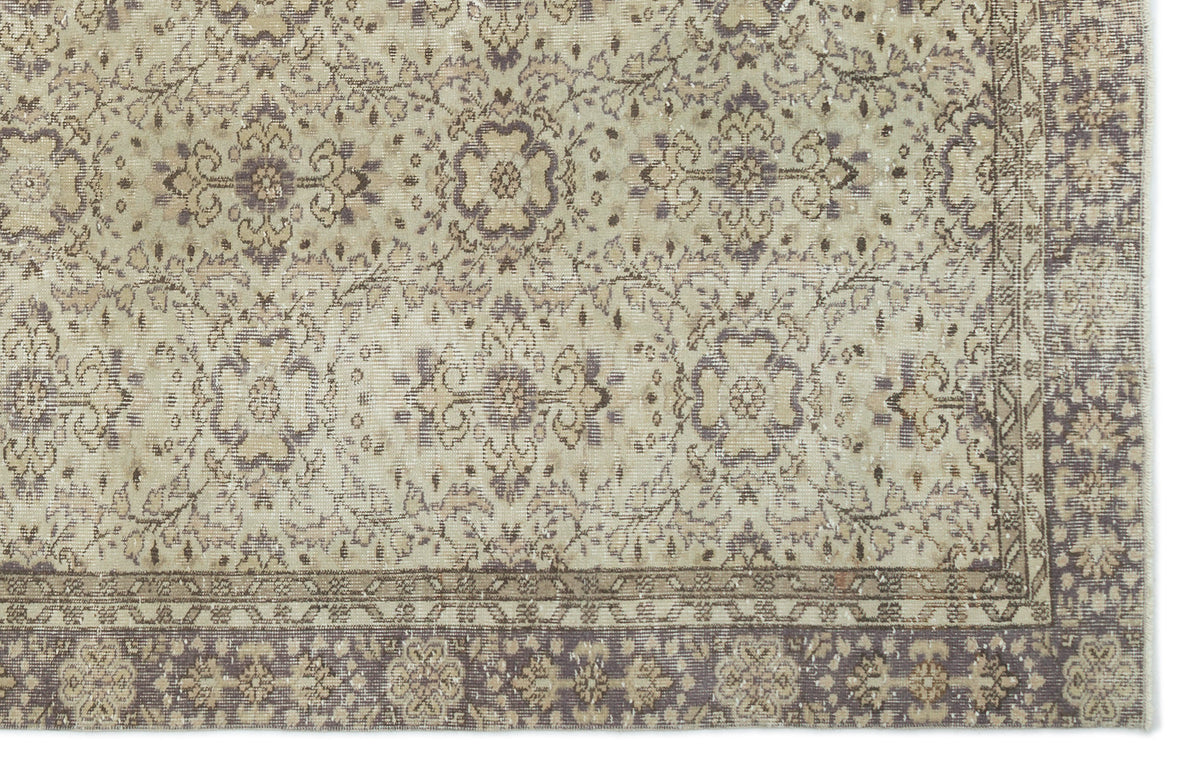 Beige and muted purple vintage-style rug with a distressed floral medallion pattern and a decorative border.