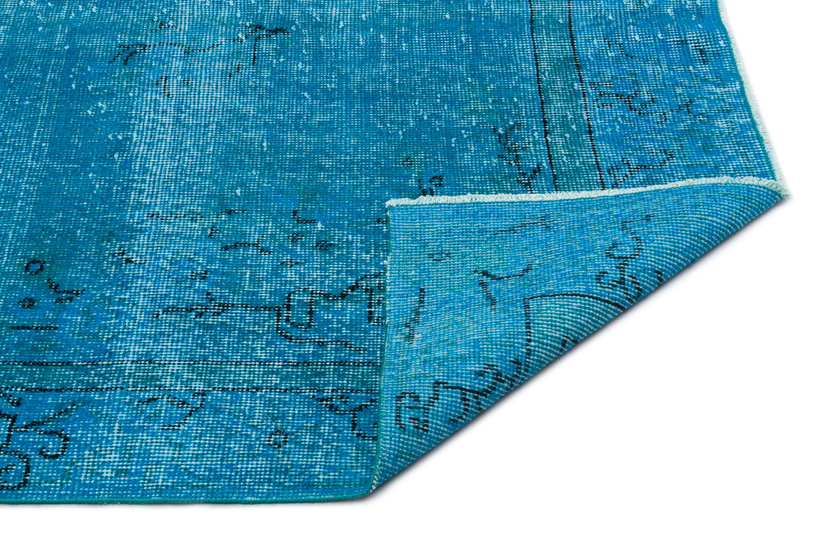 Bright blue distressed rug with a faded black geometric pattern and a folded corner, isolated on a white background.