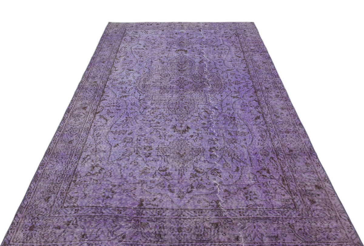 Distressed purple vintage-style rug with a dark floral medallion pattern and a bordered edge on a white background.
