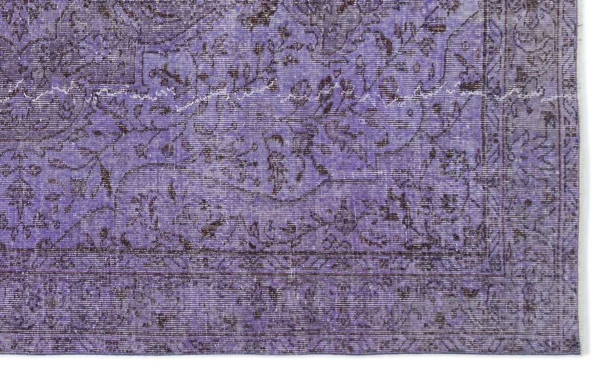 Purple and dark brown distressed rug with a traditional floral medallion pattern and a detailed border.