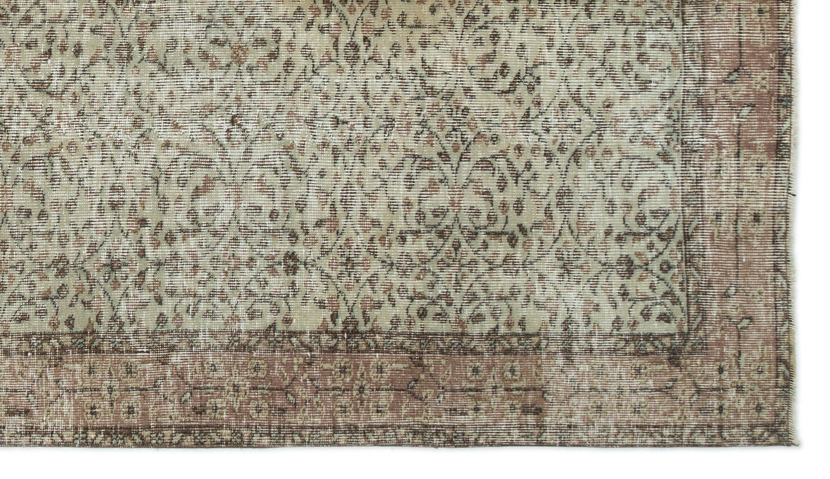 Beige and muted rose vintage-style rug with a distressed floral vine pattern and a wide decorative border.