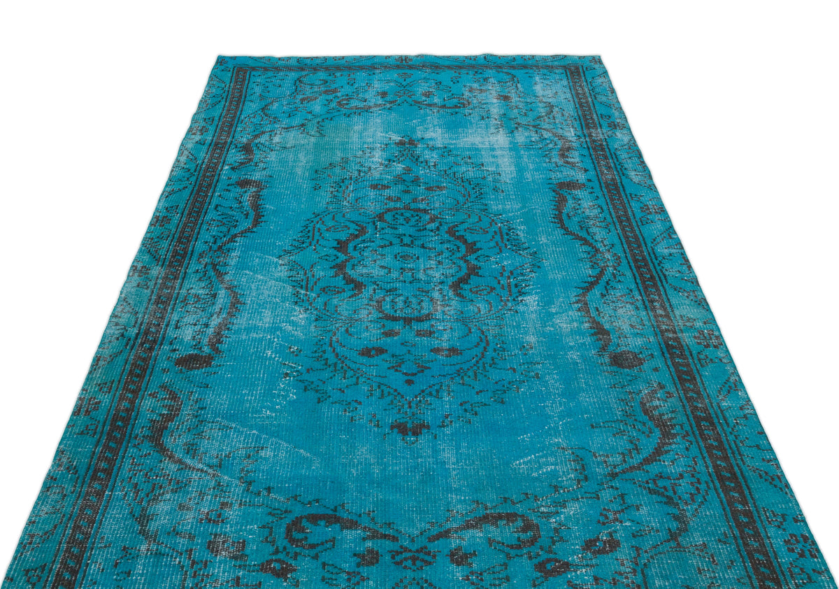 Bright turquoise distressed rug with a dark charcoal traditional medallion pattern on a white background.