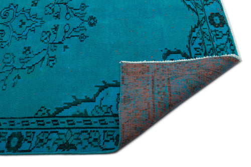 Load image 1 in gallery view. Bright turquoise rug with a black traditional floral medallion pattern, shown with a corner folded to reveal the backing.