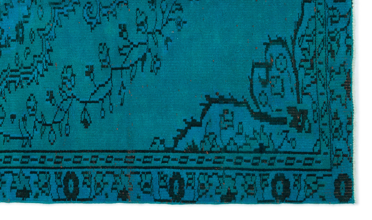Teal rug with black traditional floral motifs and a geometric border.