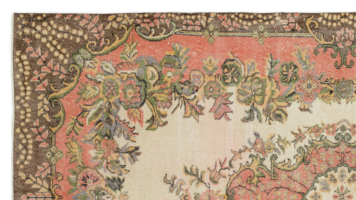 Vintage-style rug with a cream center, coral border, and intricate floral medallion pattern in green, brown, and pink.