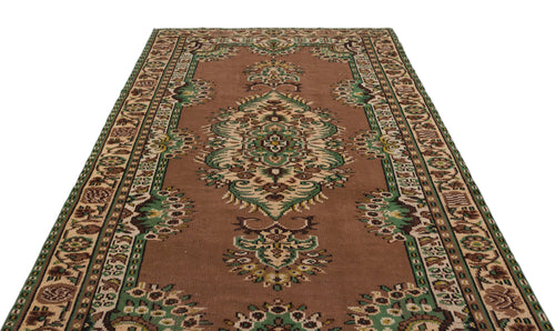 Load image 1 in gallery view. Brown traditional rug with a central green and cream floral medallion and a decorative geometric border.