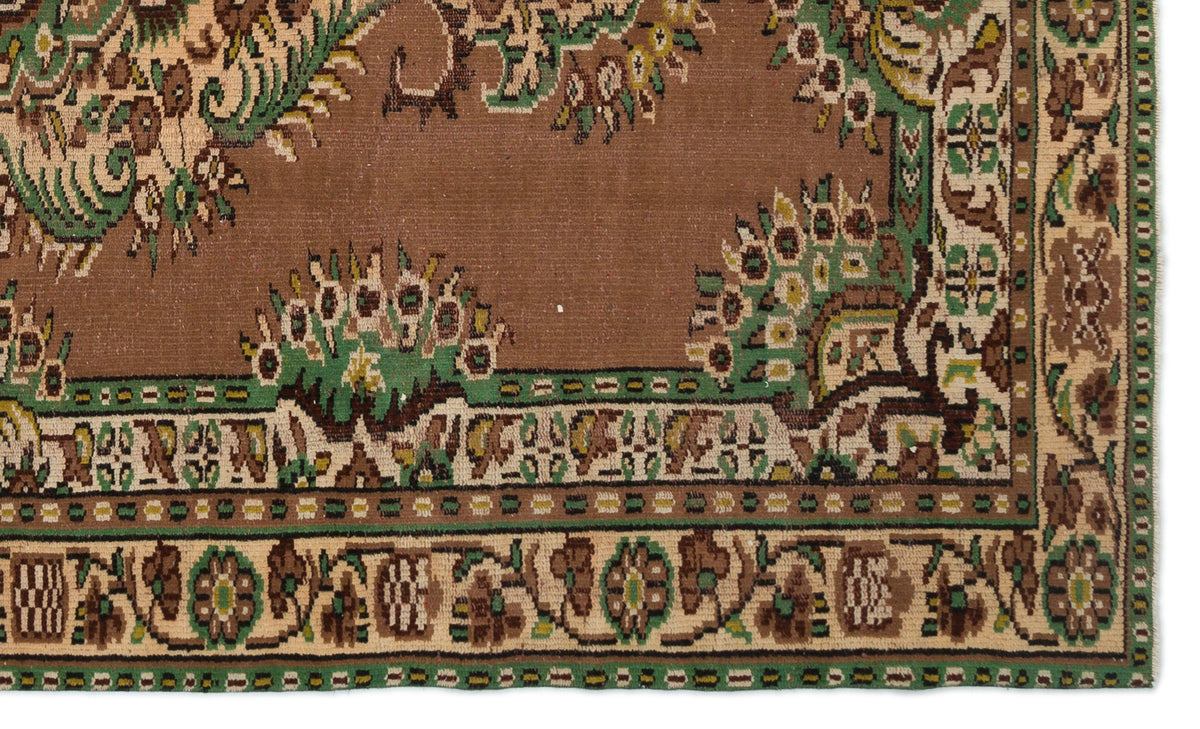 Brown traditional rug with green and cream floral motifs and a geometric border pattern.
