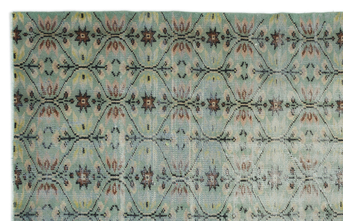 Sage green rug with a repeating diamond lattice pattern featuring brown and cream floral motifs.