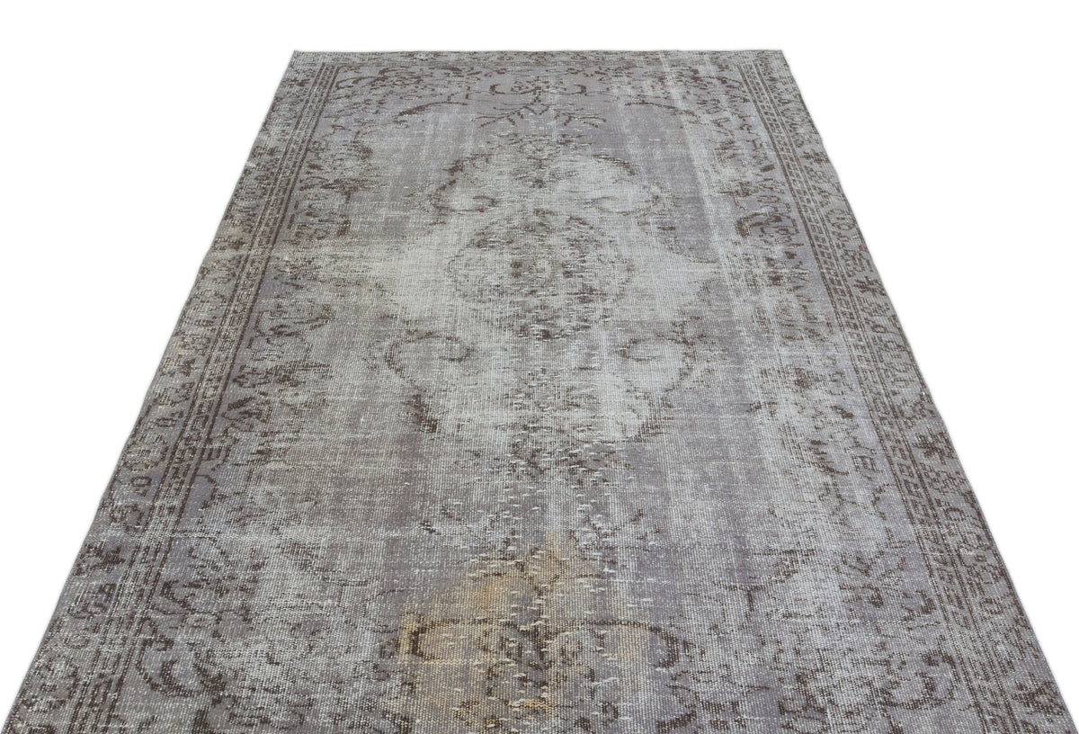 Grey and taupe vintage-style rug with a distressed central medallion and ornate border on a white background.
