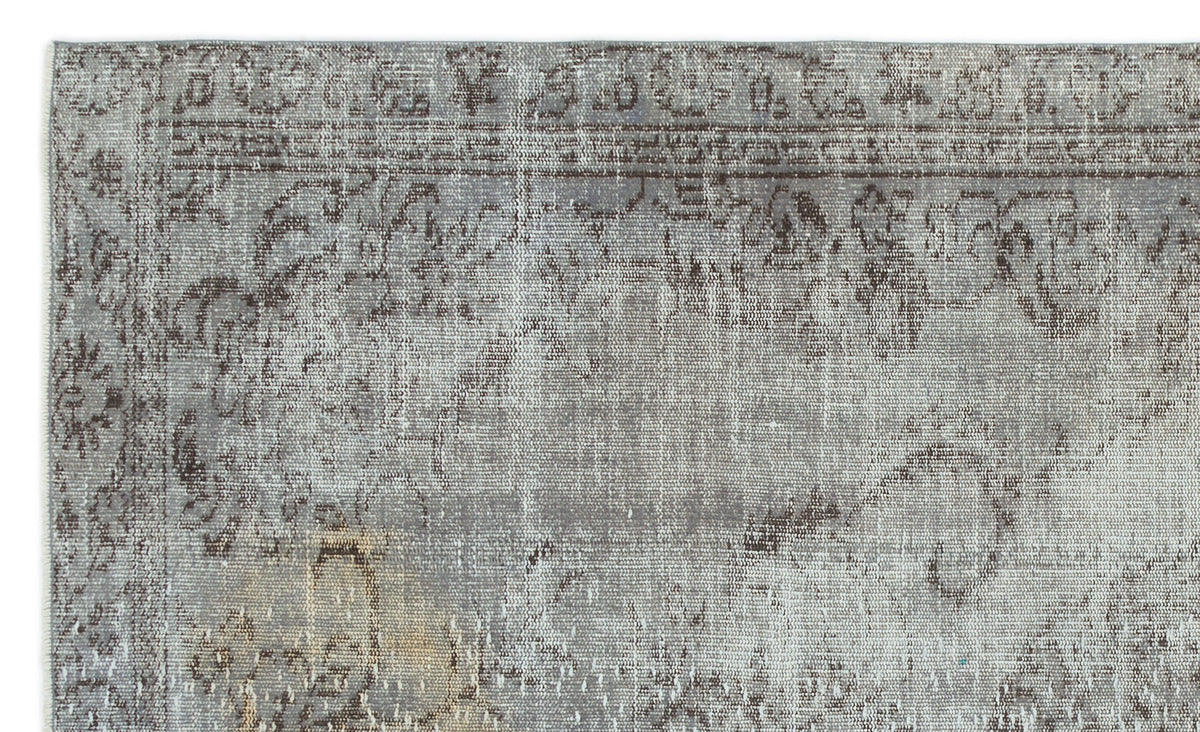 Grey and brown distressed rug with a faded traditional floral medallion pattern.