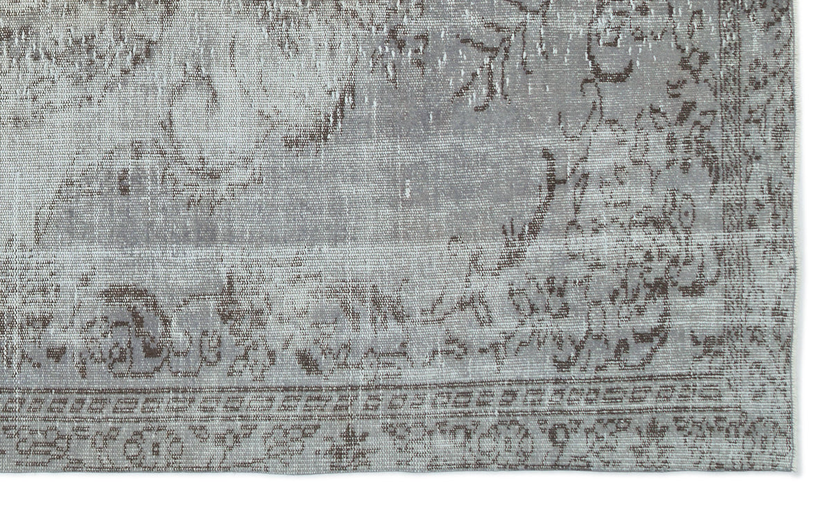 Grey and taupe distressed rug with a faded traditional floral pattern and a geometric border.