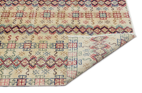 Load image 1 in gallery view. Beige rug with red, blue, and green geometric tribal patterns and a folded corner showing the reverse side.