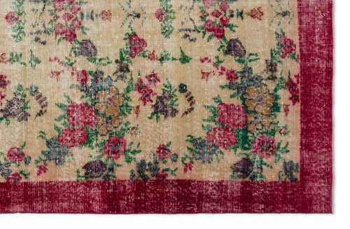 Load image 1 in gallery view. Beige vintage-style rug with a distressed floral pattern in red, green, and purple, featuring a solid red border.