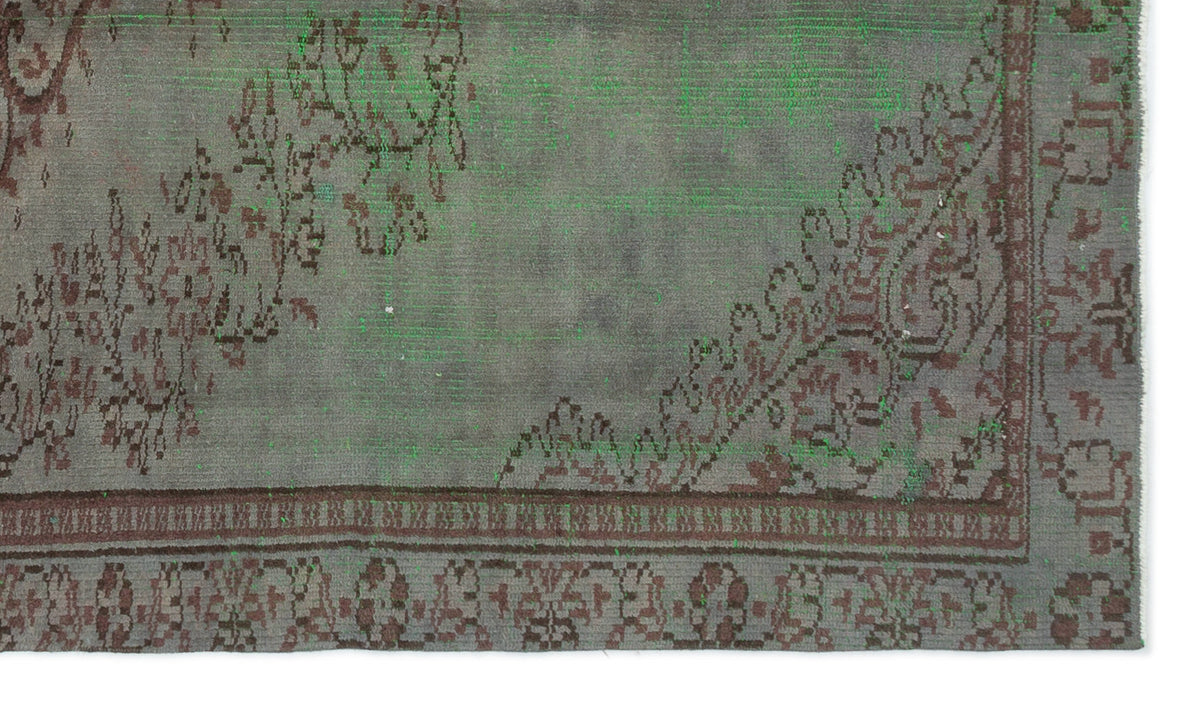 Distressed grey and brown rug with a traditional floral medallion border and overdyed green accents.