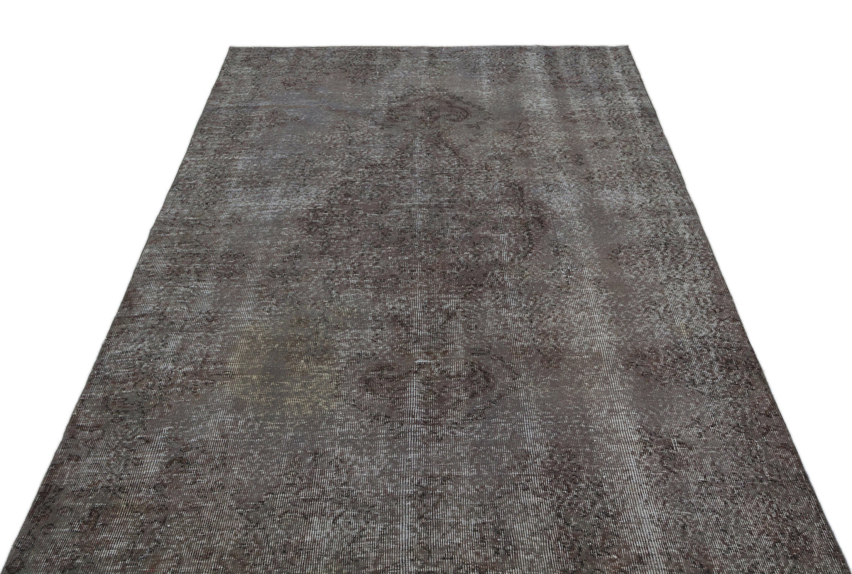 Dark charcoal distressed rug with a faded traditional medallion pattern on a white background.