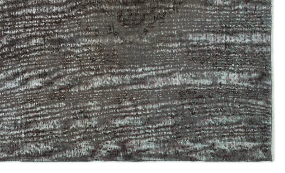 Charcoal grey distressed rug with a faded traditional floral medallion pattern.