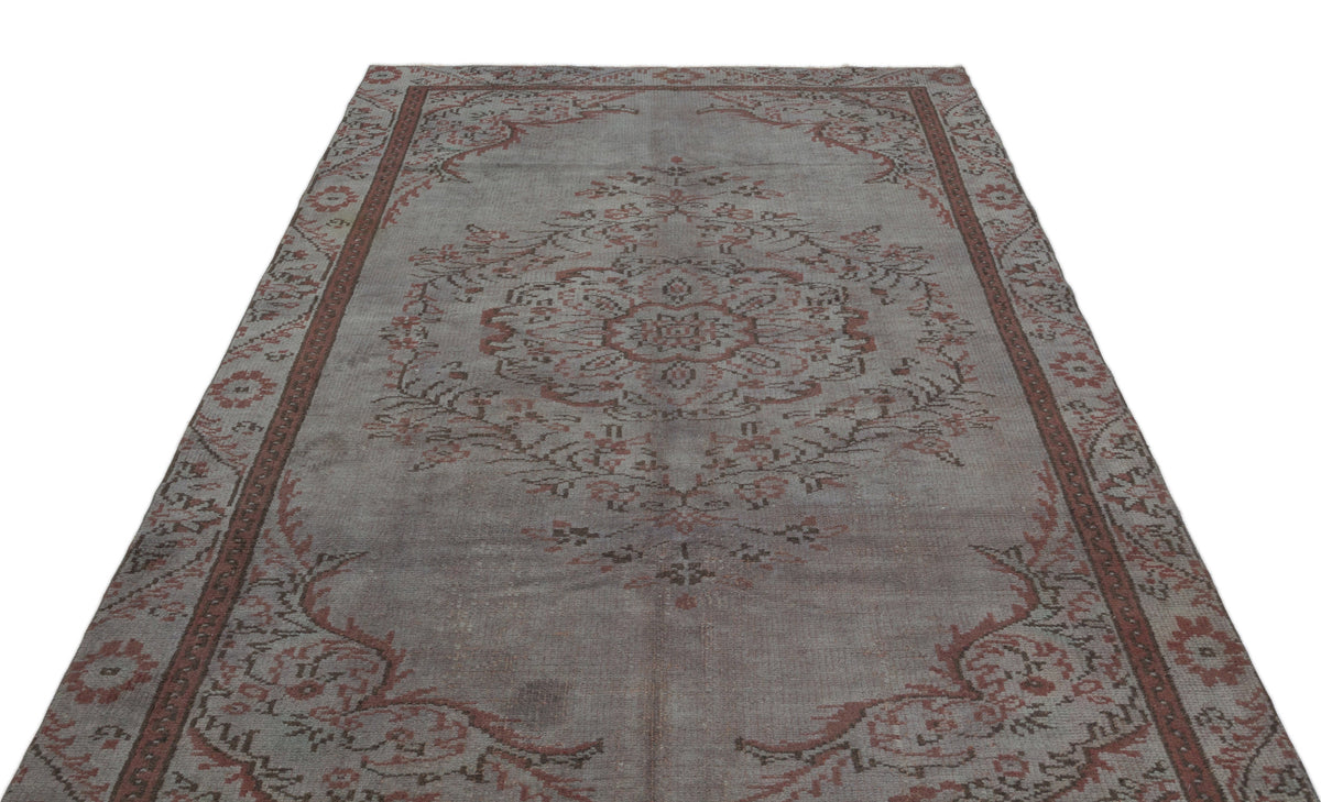 Distressed grey and terracotta rug with a central floral medallion and ornate border pattern on a white background.