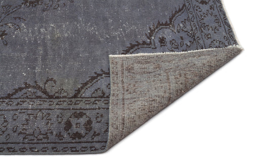 Load image 1 in gallery view. Slate blue distressed rug with a dark charcoal floral border, shown with a corner folded to reveal the woven backing.