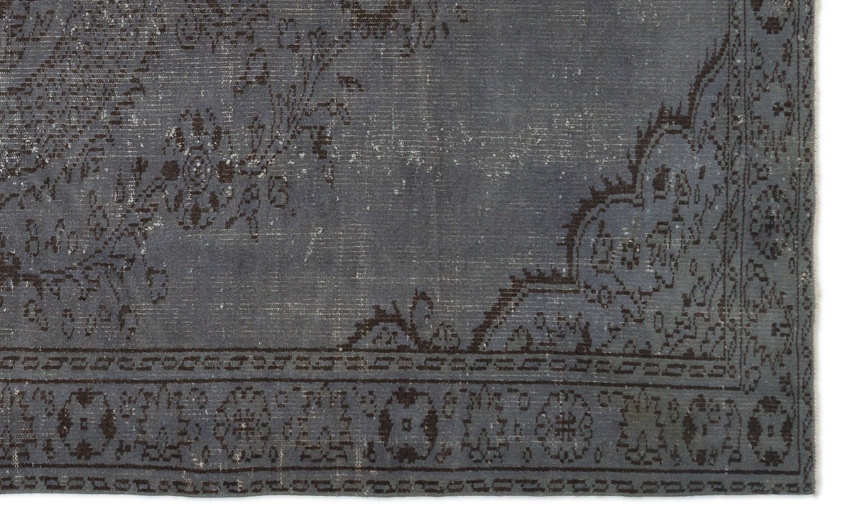 Charcoal grey distressed rug with a faded floral medallion pattern and a geometric border.