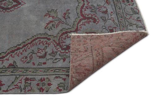Load image 1 in gallery view. Grey rug with a red and olive floral medallion pattern, shown with a corner folded to reveal the textured underside.