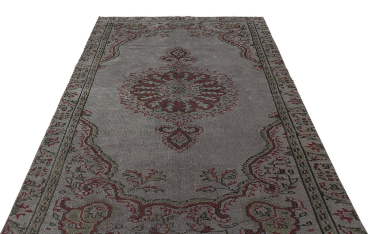 Grey vintage-style rug with a central red and olive green floral medallion and a decorative border.