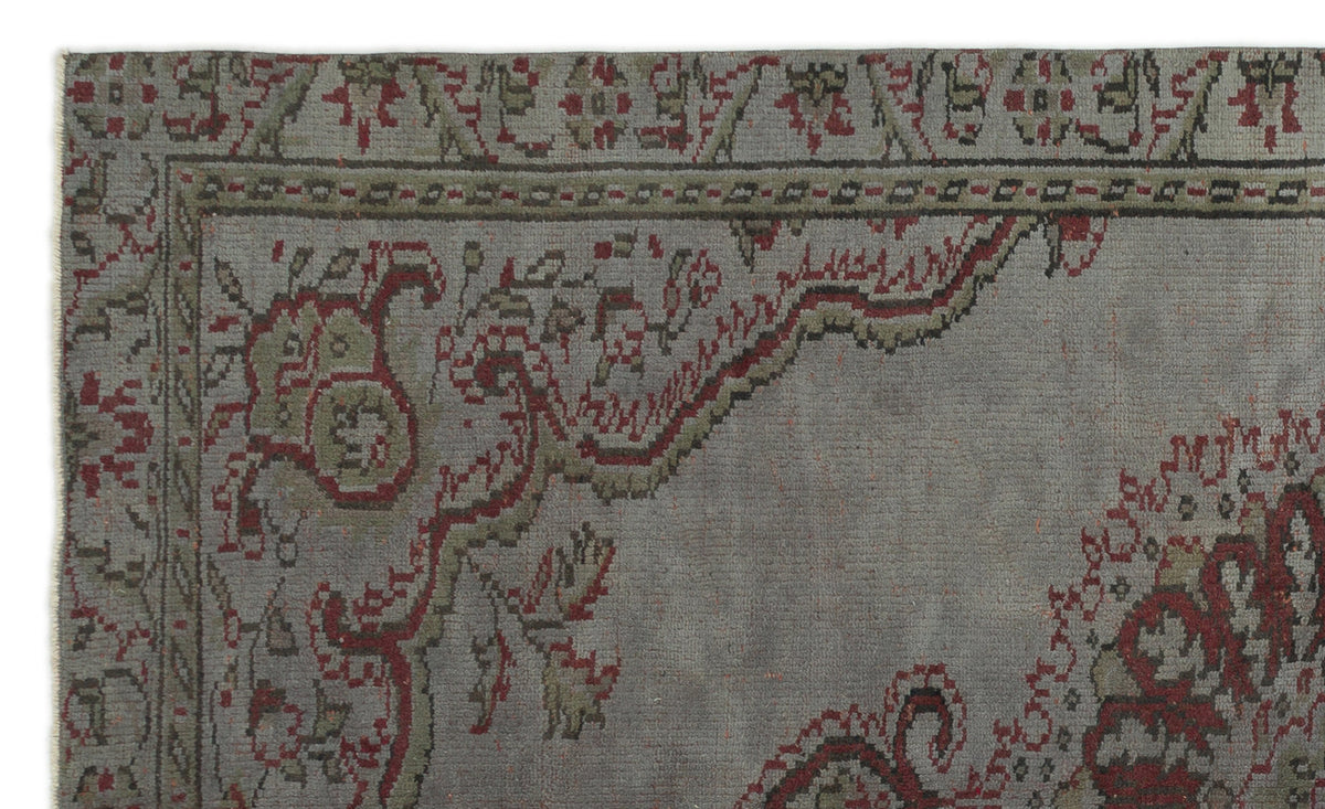 Grey rug with a distressed traditional floral medallion pattern in muted red and olive green.