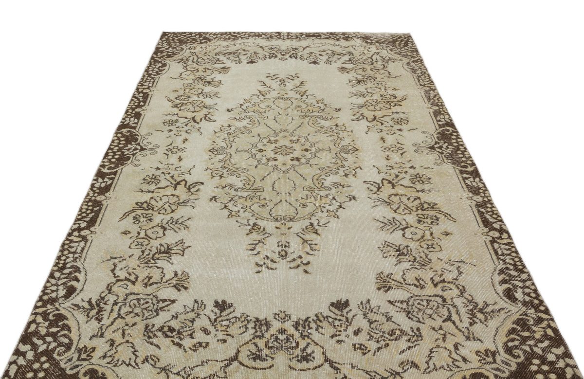 Beige and brown vintage-style rug with a central floral medallion and ornate border on a white background.