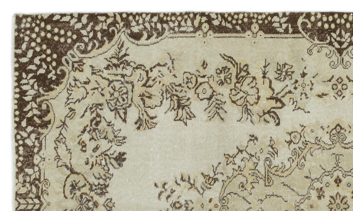 Distressed beige and brown rug with a traditional floral medallion pattern and a wide decorative border.