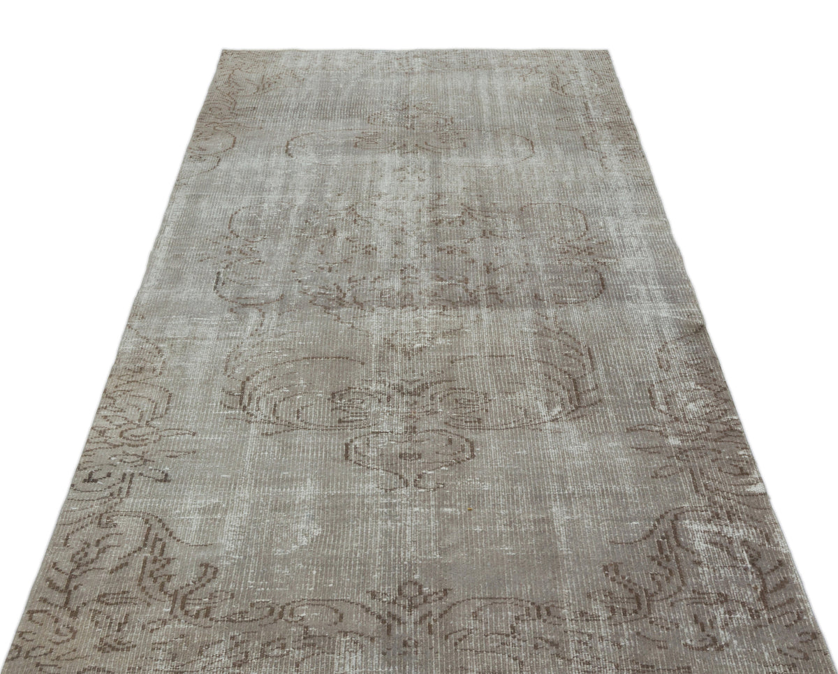 Taupe and grey distressed vintage-style rug with a faded traditional medallion pattern on a white background.
