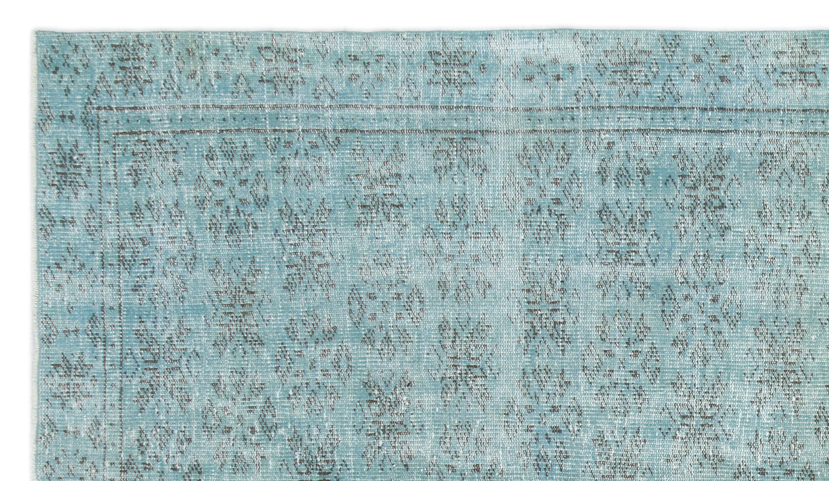 Light blue distressed rug with a faded grey floral medallion pattern and a bordered edge.