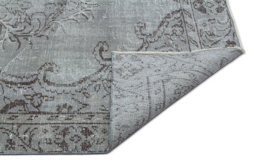 Load image 1 in gallery view. Grey and brown distressed traditional rug with a floral medallion pattern, shown with a corner folded over.