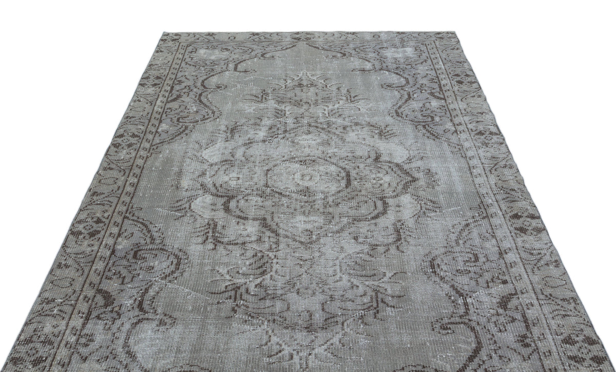Grey and brown distressed vintage-style rug with a central floral medallion and ornate border.