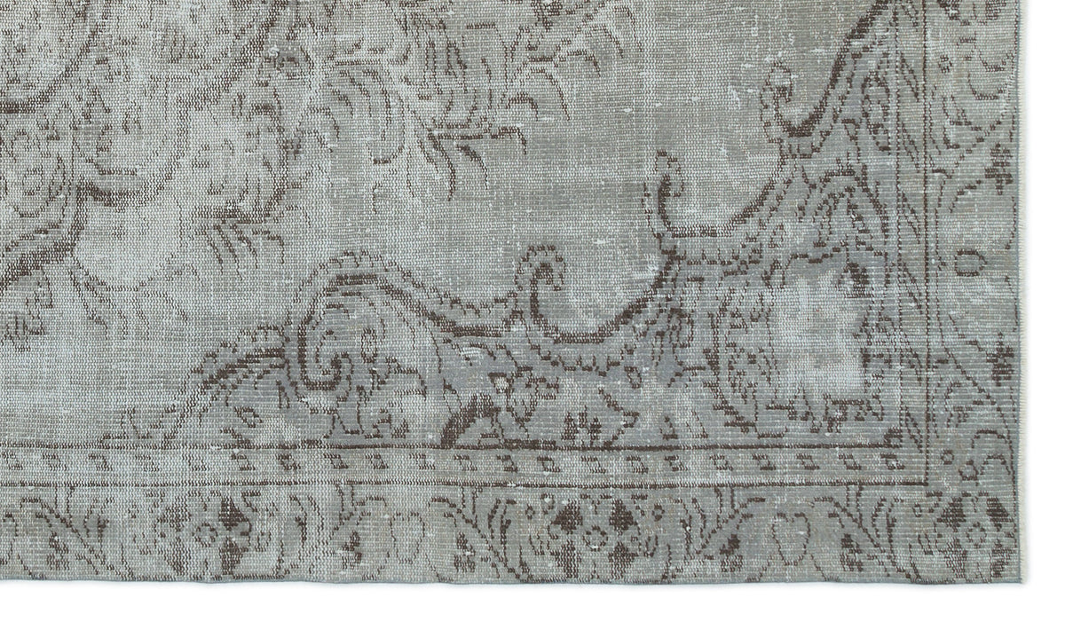 Grey and brown distressed rug with a traditional ornate floral medallion pattern and a bordered edge.