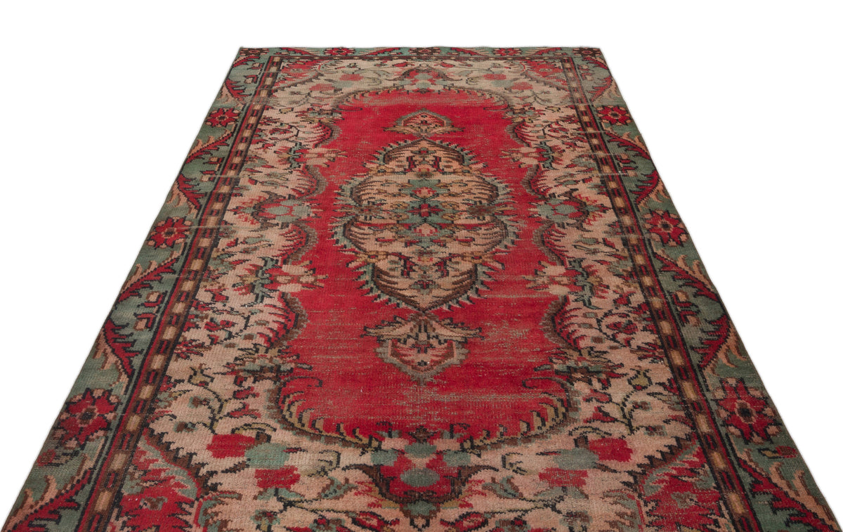 Red, green, and beige vintage-style rug with a central floral medallion and ornate border pattern.