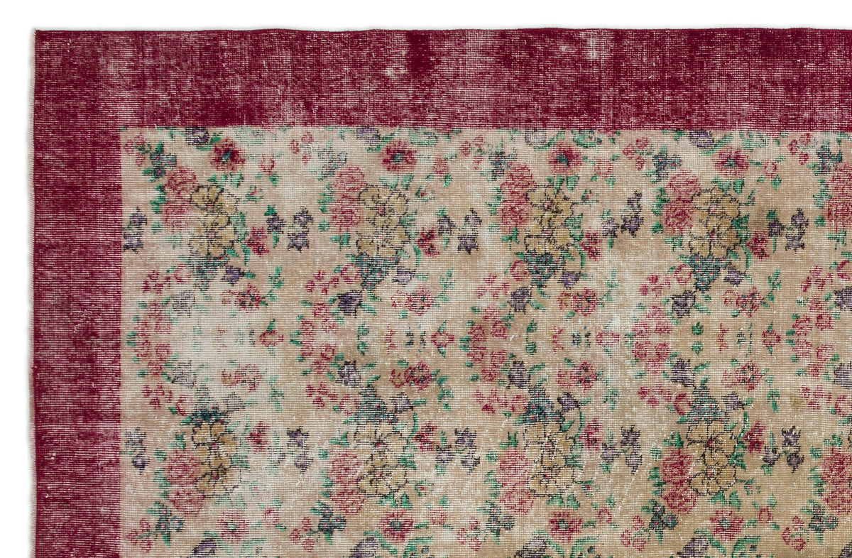 Distressed beige rug with a floral pattern in red, yellow, and green, featuring a solid deep red border.