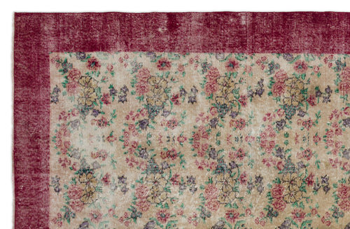 Load image 1 in gallery view. Distressed beige rug with a floral pattern in red, yellow, and green, featuring a solid deep red border.