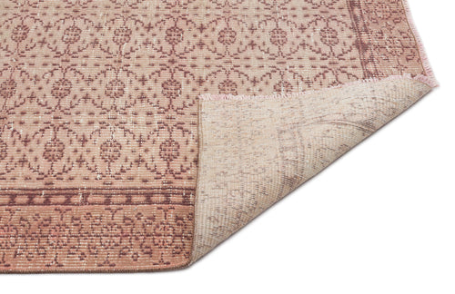Load image 1 in gallery view. Dusty rose and cream rug with a repeating floral medallion pattern and a folded corner showing the woven backing.