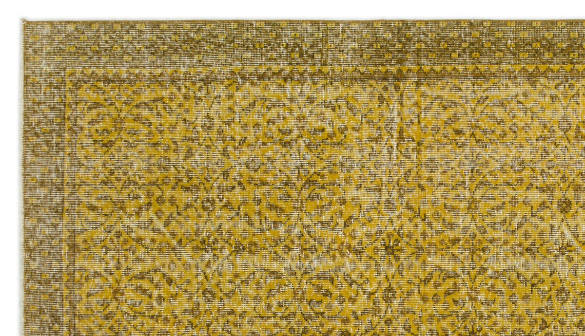 Mustard yellow and brown distressed rug with a traditional floral medallion pattern and a geometric border.