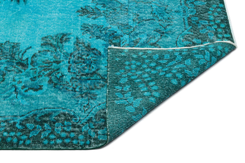 Load image 1 in gallery view. Bright turquoise and dark teal rug with a distressed floral pattern, shown with a corner folded to reveal the backing.