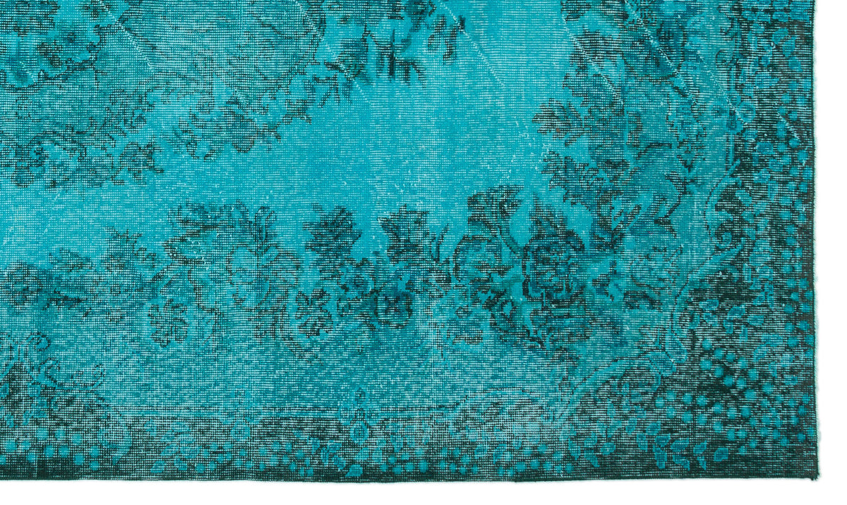 Bright turquoise rug with a distressed black floral medallion pattern and a dark border.