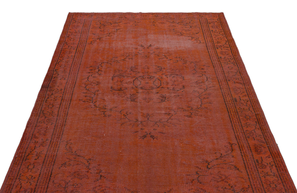 Distressed terracotta rug with a dark brown central floral medallion and geometric border pattern.