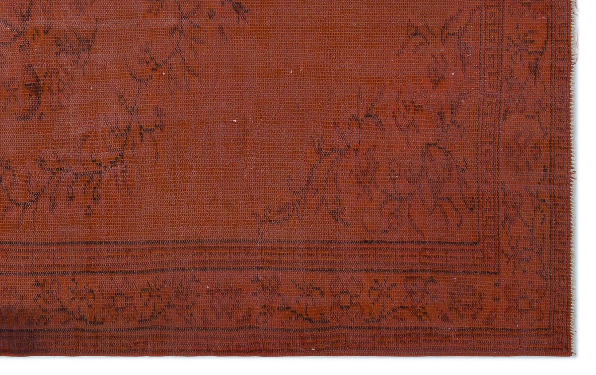 Rust-colored rug with a dark brown floral border and faint, distressed botanical motifs on a white background.