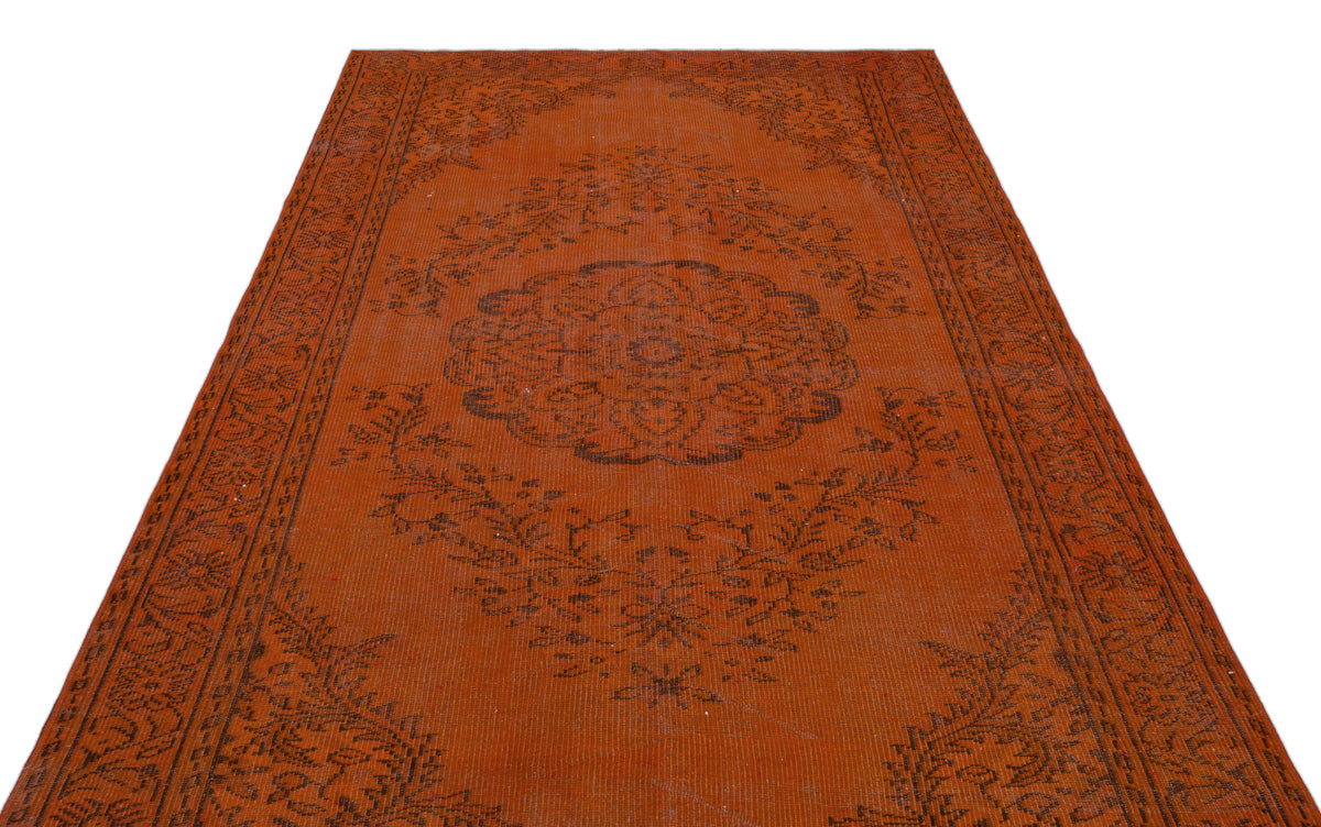Burnt orange vintage-style rug with a dark brown central floral medallion and ornate border pattern.