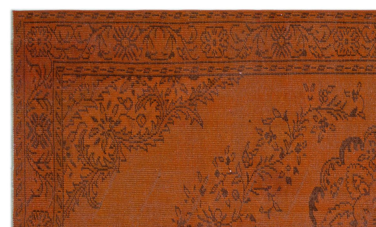 Rust-colored rug with a dark brown floral border and intricate botanical motifs.