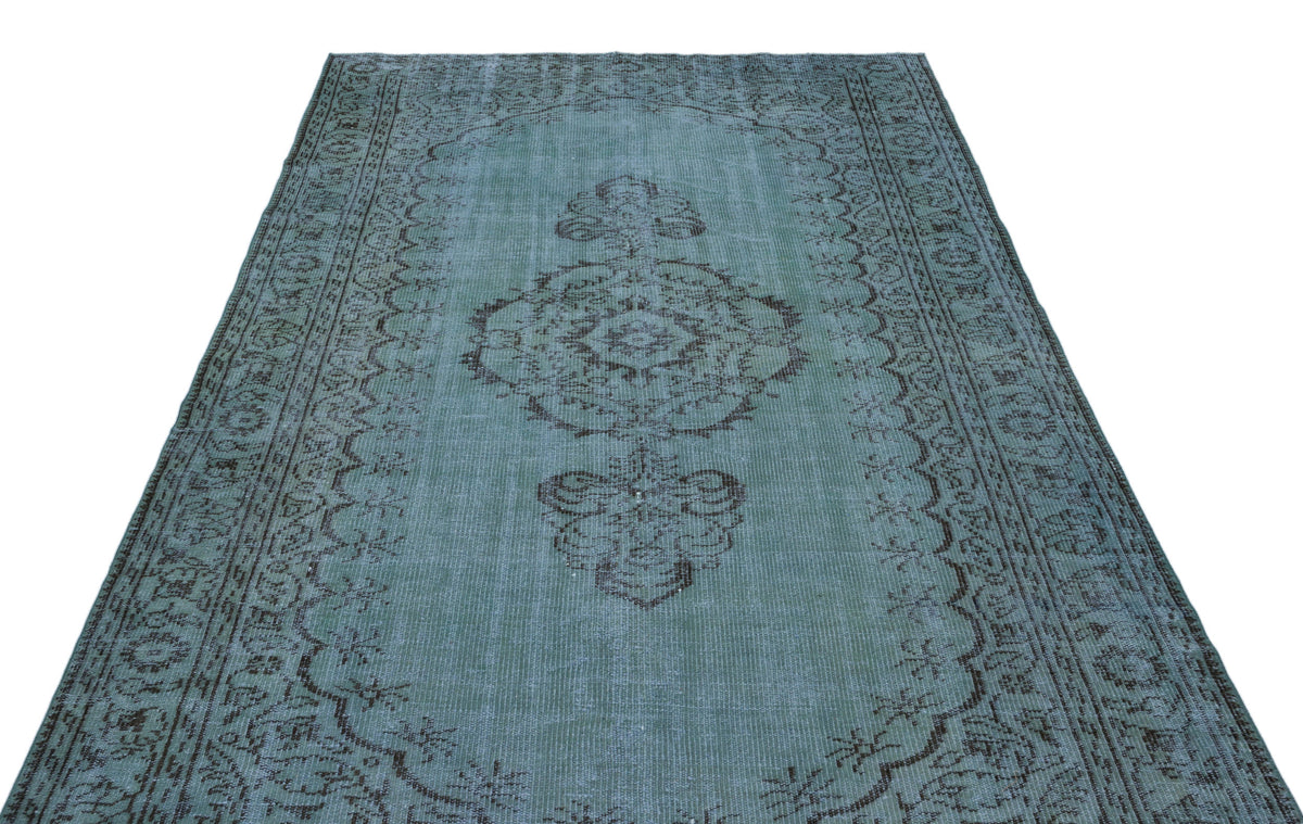 Distressed teal and charcoal rug with a central medallion and ornate border pattern on a white background.