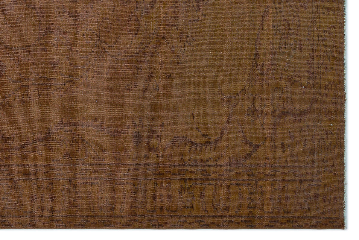 Solid brown rug with a subtle, distressed traditional medallion pattern and a thin border.