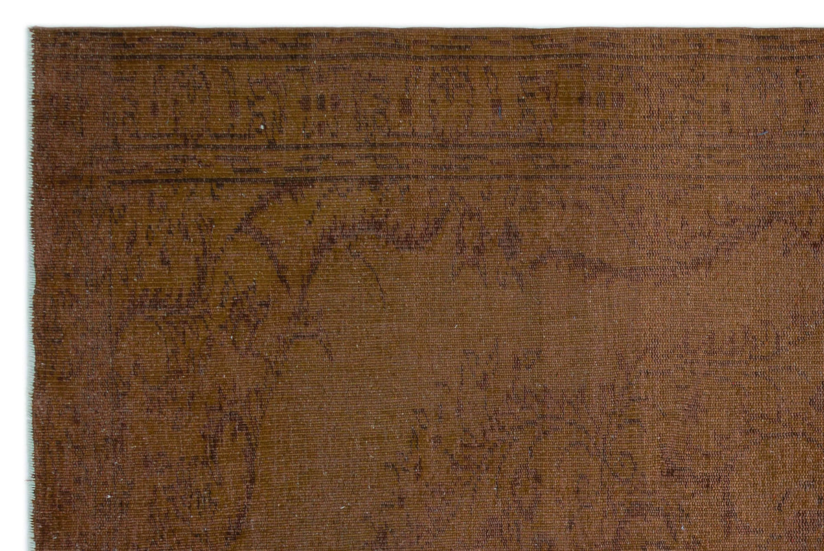 Solid brown rug with a subtle, distressed tonal pattern and a linear border detail.