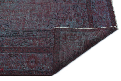 Load image 1 in gallery view. Deep burgundy and slate blue distressed rug with a geometric border pattern, shown with a folded corner.