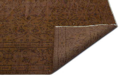 Load image 1 in gallery view. Brown distressed rug with a subtle floral pattern and a folded corner revealing the underside, on a white background.